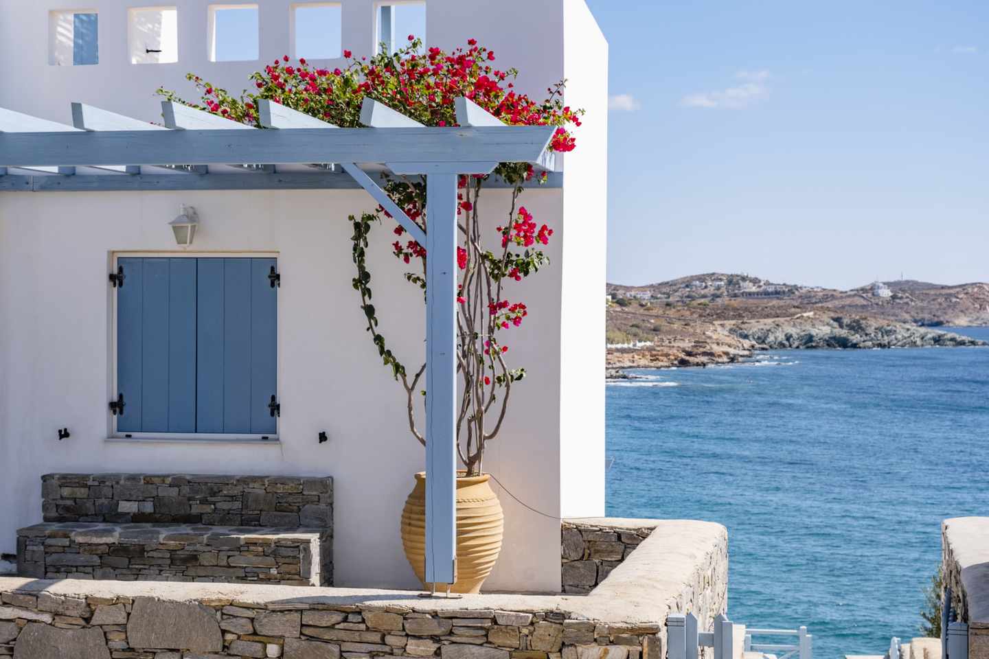 blt3925252c2175176f-griechenland-syros-g-1358090852-1.jpg Weißes Cottage mit blauen Fenstern, Meer im Hintergrund auf einer Griechischen Insel