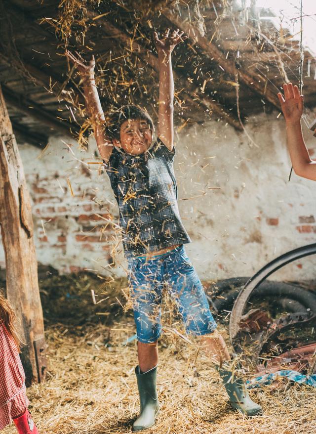 Kinder spielen auf dem Bauernhof im Stroh