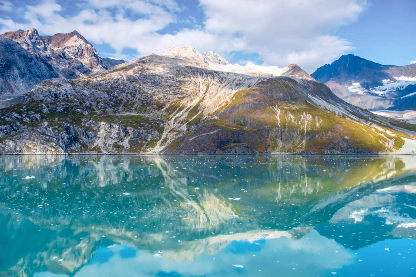 Gletschersee mit spiegelnder Wasseroberfläche vor schroffen Bergen im Glacier Bay National Park in Alaska