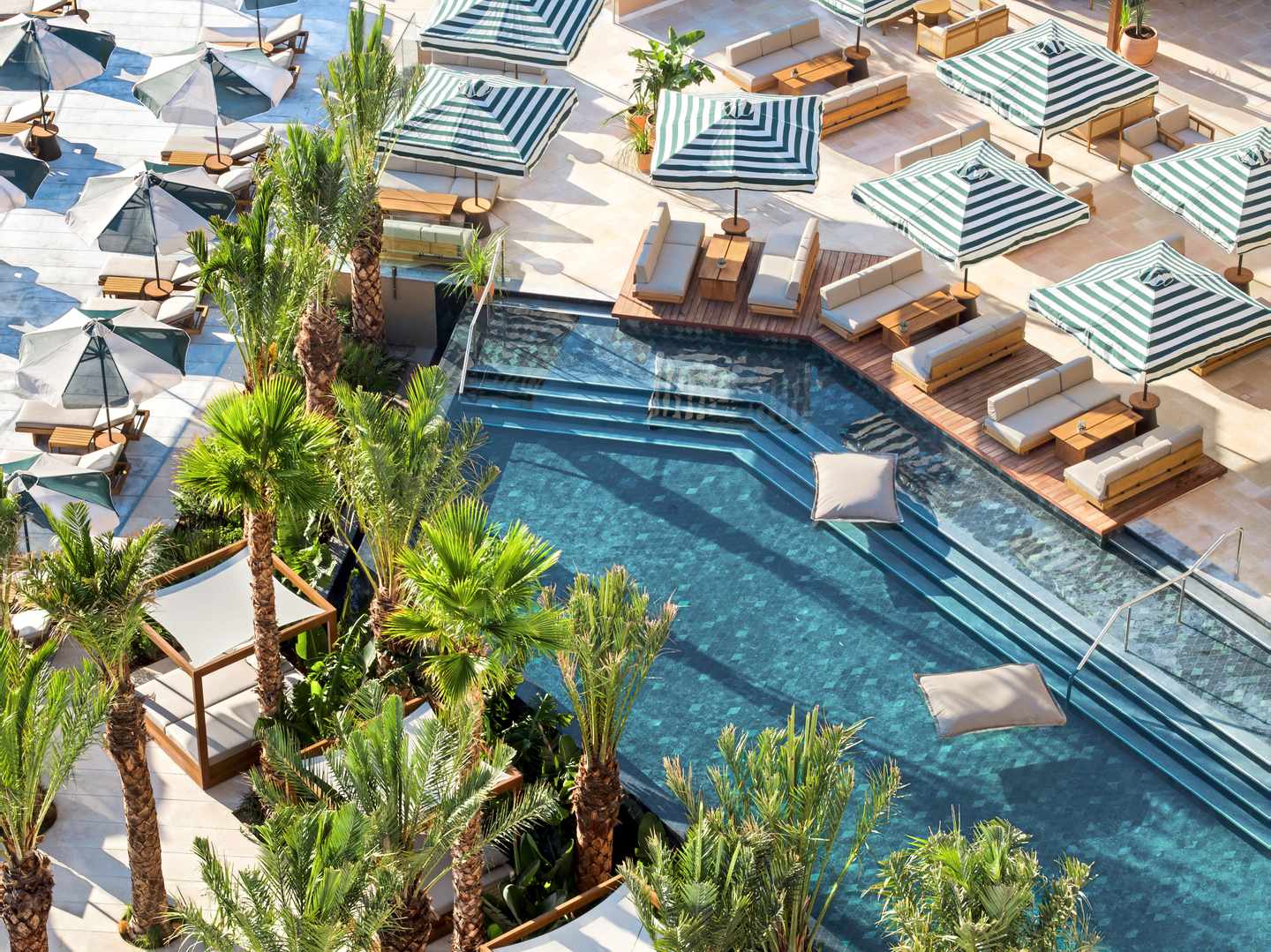 Pool mit grünen Palmen und Sonnenliegen und Schirmen