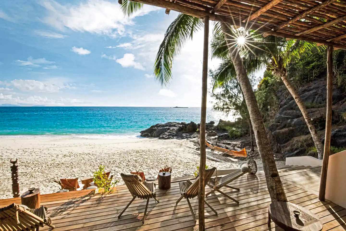 Terrasse eines Bungalows im Constance Tsarabanjina, Madagaskar, mit Holzliegen, Hängematte und direktem Blick auf den Strand der Insel