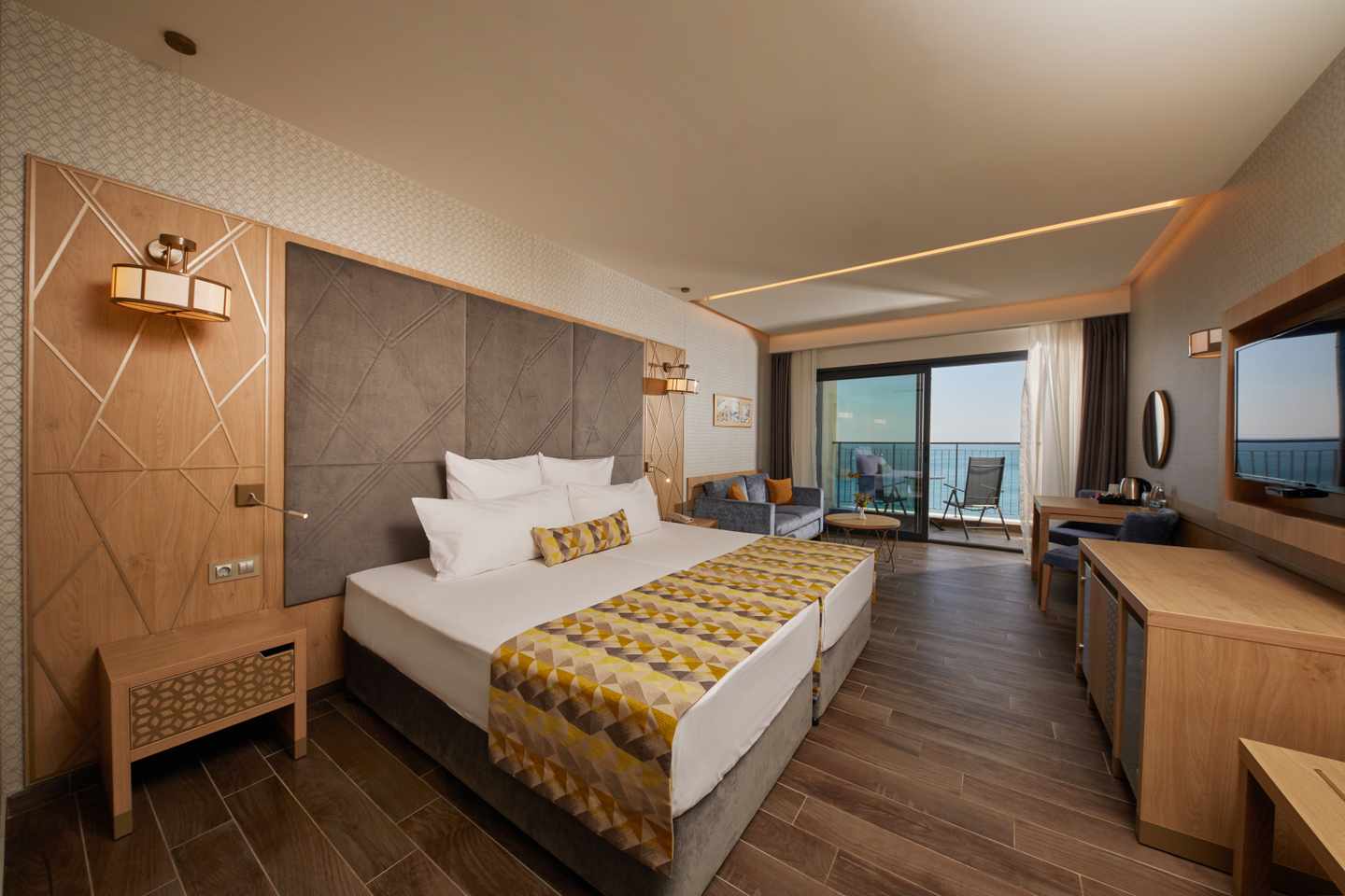 Zimmer mit Doppelbett, Holzmöbeln  und goldenen Akzenten im Secrets Sunny Beach Resort and Spa