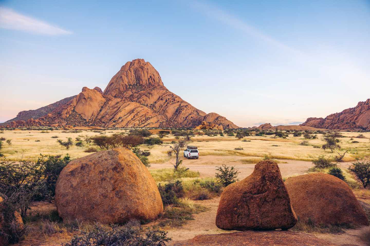 GettyImages-2222889084-3.jpg Wohnmobil zwischen Granitfelsen und trockenem Gras vor der Spitzkoppe in Namibia bei Sonnenaufgang