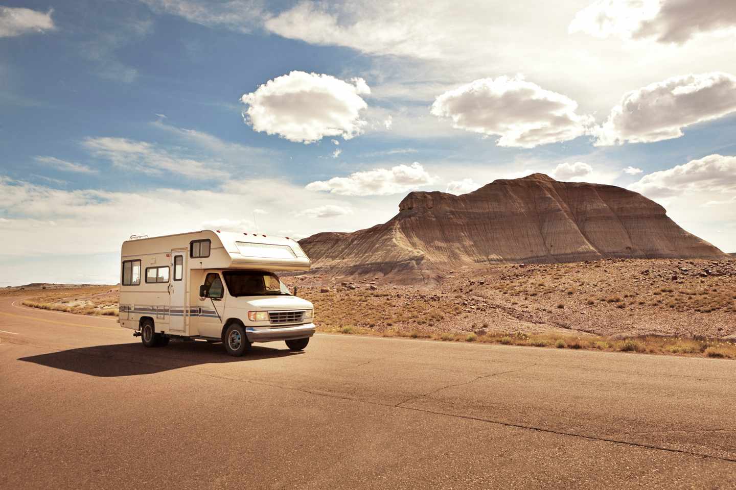 Pickup-Camper-Wohnmobil auf einer Rundreise durch den amerikanischen Südwesten auf einer asphaltierten Straße im Petrified Forest National Park Arizona USA. Das Wohnmobil passiert die ikonische Wüstenlandschaft dieses beliebten Reiseziels.