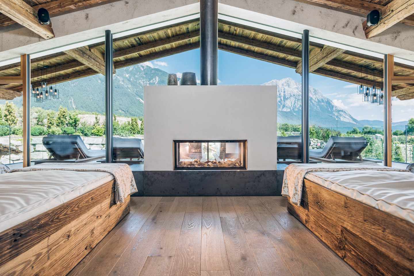 Der Wellnessbereich des Alpenresort Schwarz  mit Kamin vor Glasfensterfront