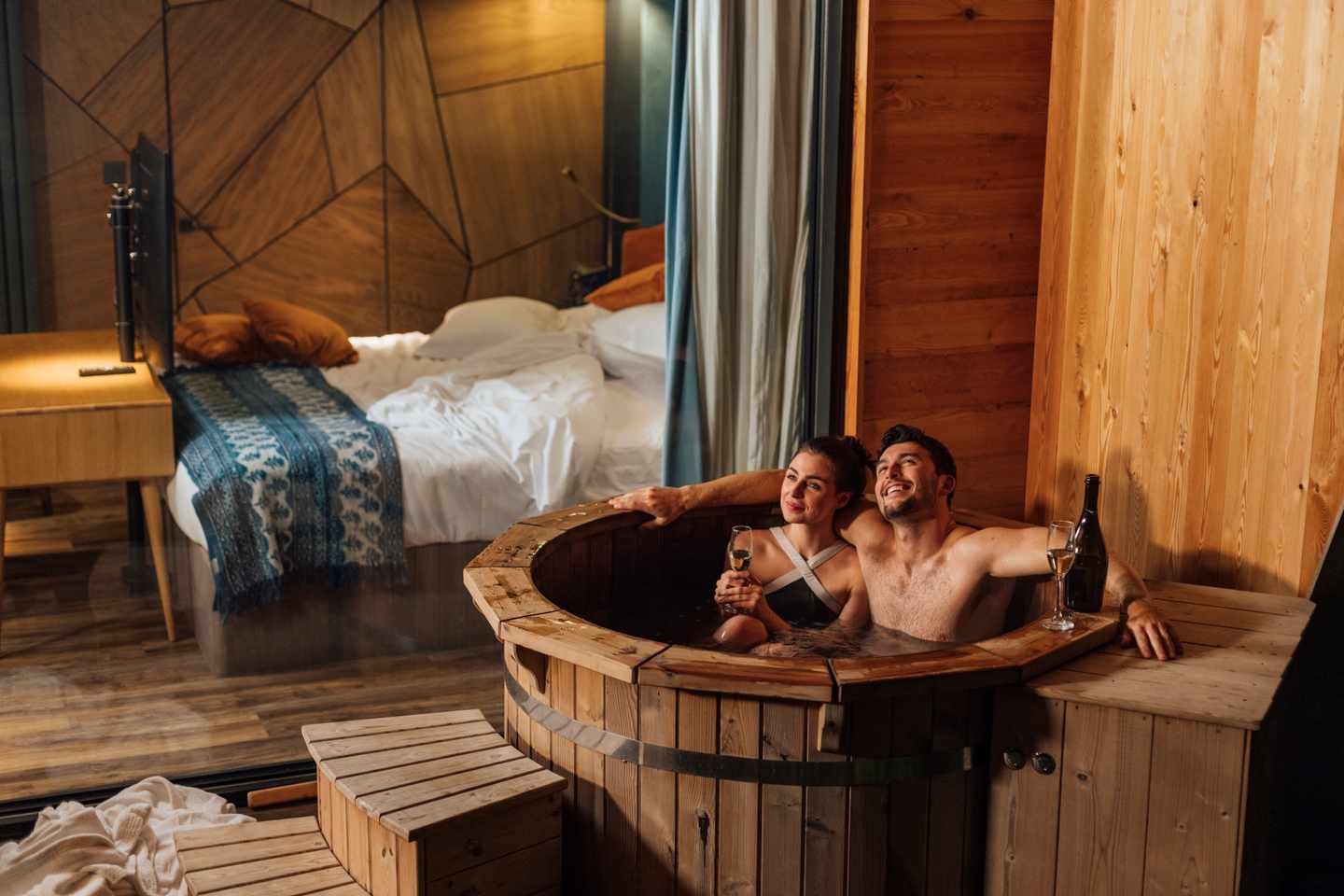 Paar entspannt während eines Wellnessurlaubs im beheizten Badezuber einer Berghütte mit Blick auf die Natur