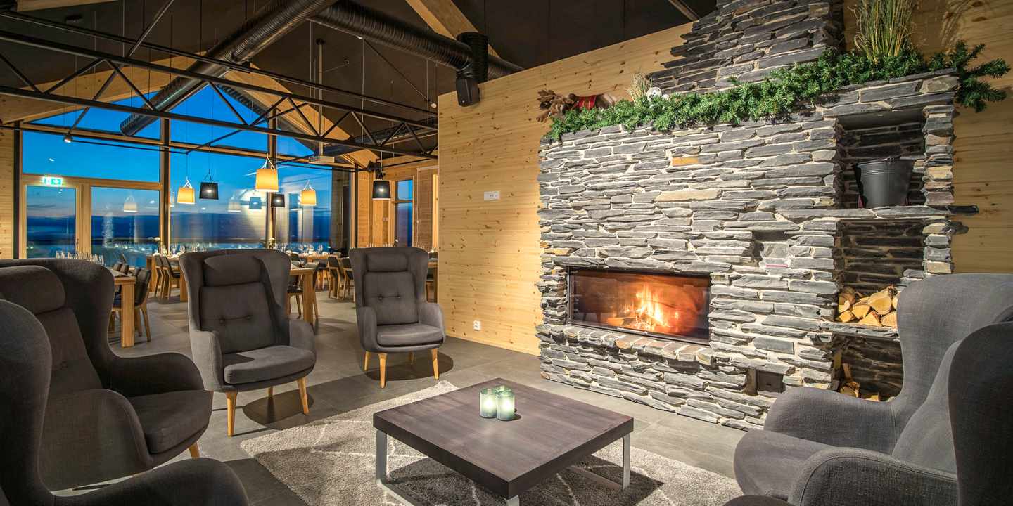 blte23ac391d29bab49-polarlichter-hotels-Star_Arctic_Hotel-DER1309438.jpg Blick in die Lounge des Star Arctic Hotels mit gemütlichen Sesseln und Kaminfeuer