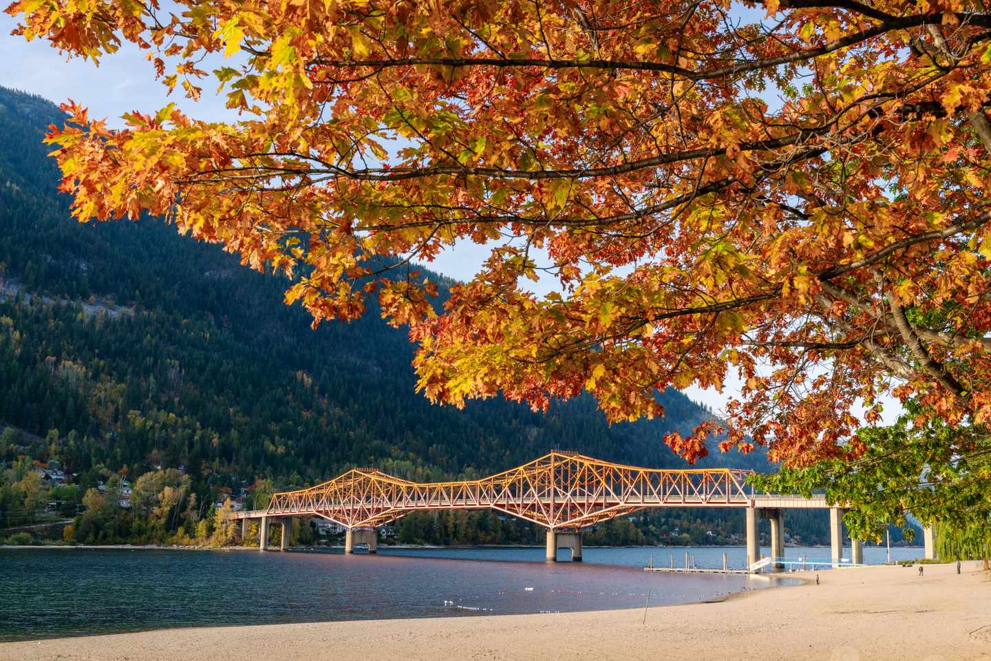 Big Orange Bridge über den Kootenay River mit herbstlichem Laub und bewaldeten Bergen bei Nelson in British Columbia