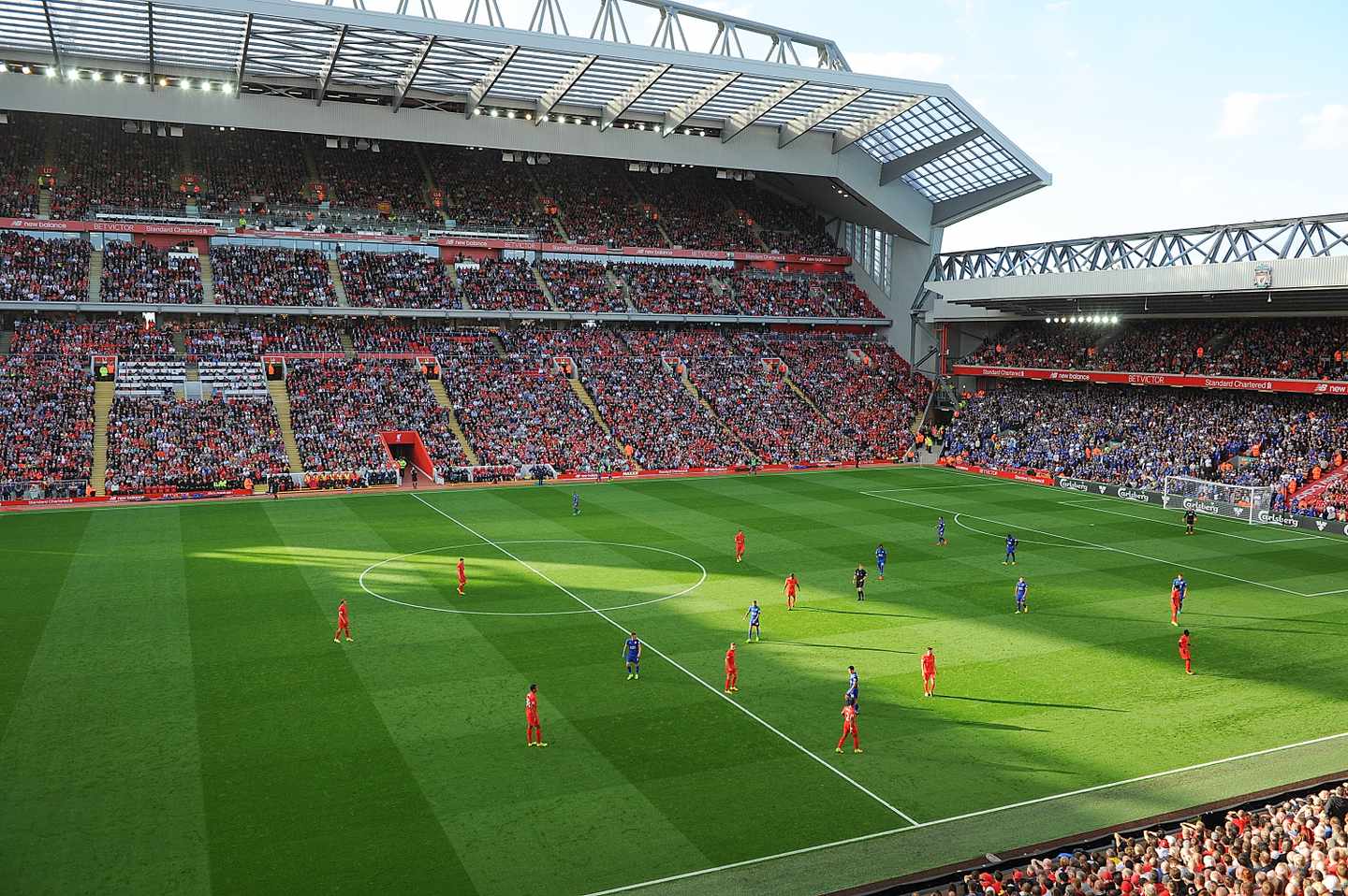 Anfield Stadium mit grünem Rasen und roten und blauen Fußballspielern auf dem Feld - während eines Fußballspiels