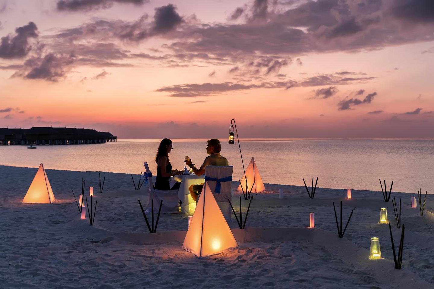 malediven-leuchtender-strand-und-meer-ein-paar-hat-ein-romatisches-date-beim-sonnenuntergang-am-strand-g-1028749064.jpg