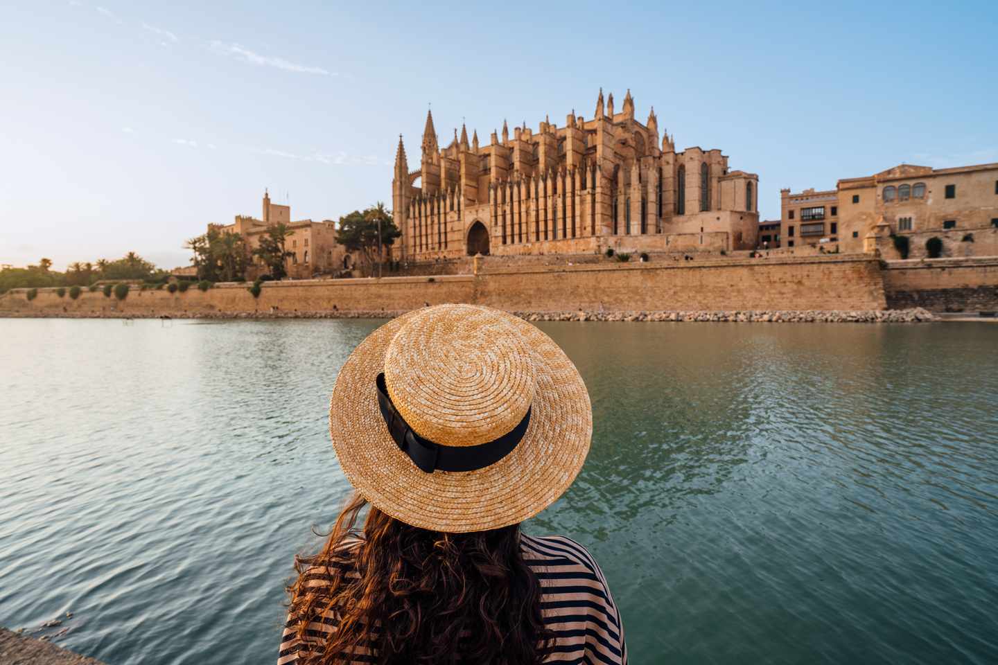 Frau mit Strohhut blickt über den Parc de la Mar auf die Kathedrale La Seu in Palma de Mallorca