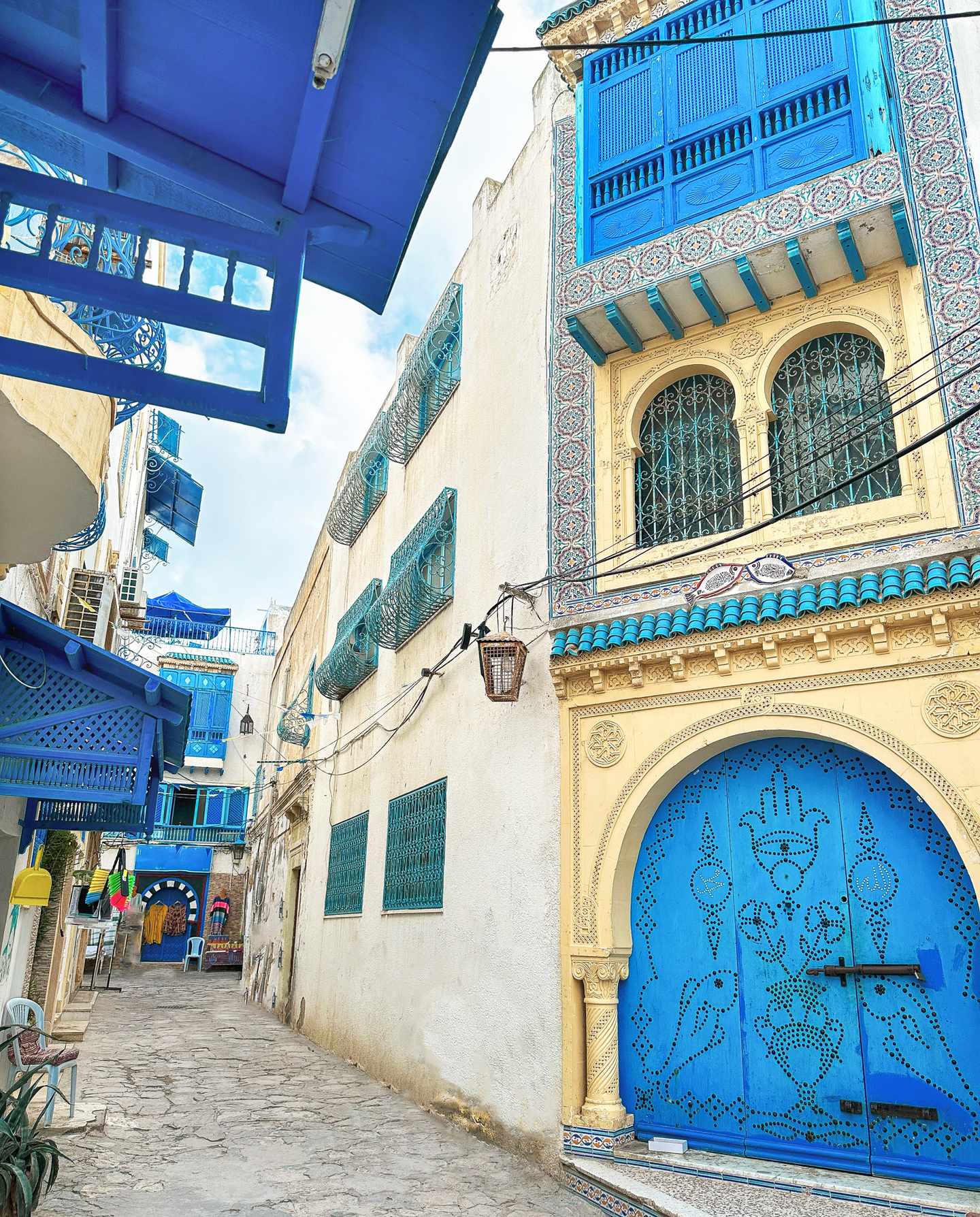 Verzierte Fassade mit blauen Fenstern und Tor in der Medina von Hammamet, schmale Gasse der historischen Altstadt