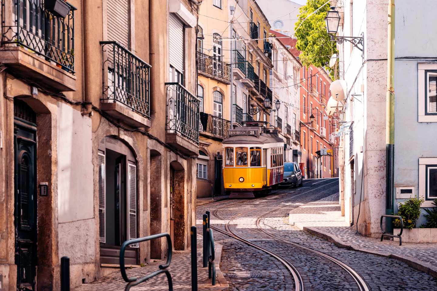 Eine gelbe Straßenbahn fährt durch die verwinkelten Gassen von Lissabon