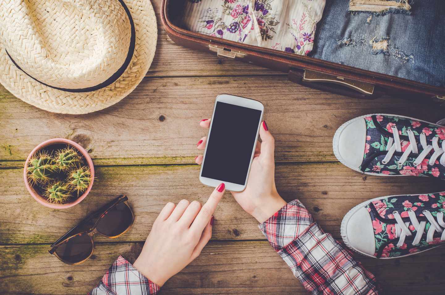 nachhaltige-reisevorbereitungen-smartphone-koffer-hut-turnschuhe-holztisch-g-819273048.jpg