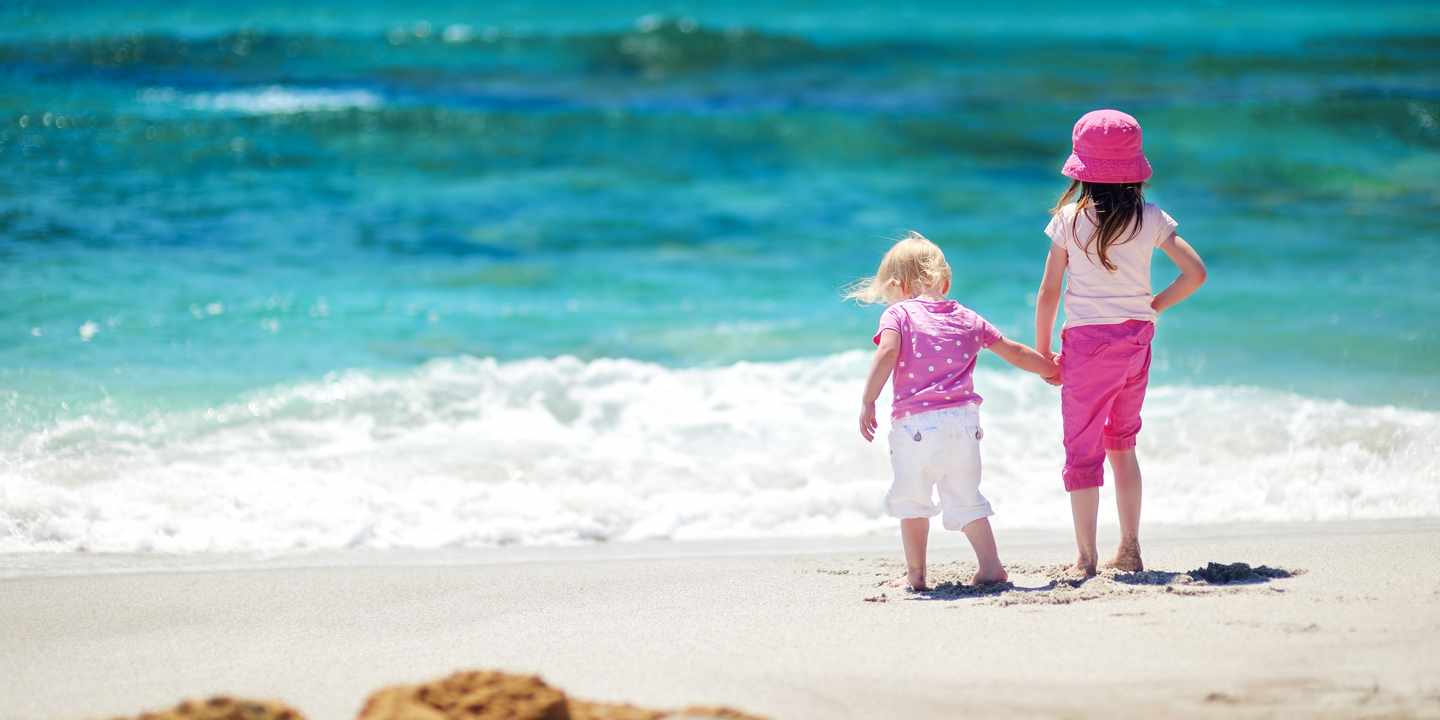familienrundreise-zwei-kleine-maedchen-stehen-am-strand-g-1168280438.jpg