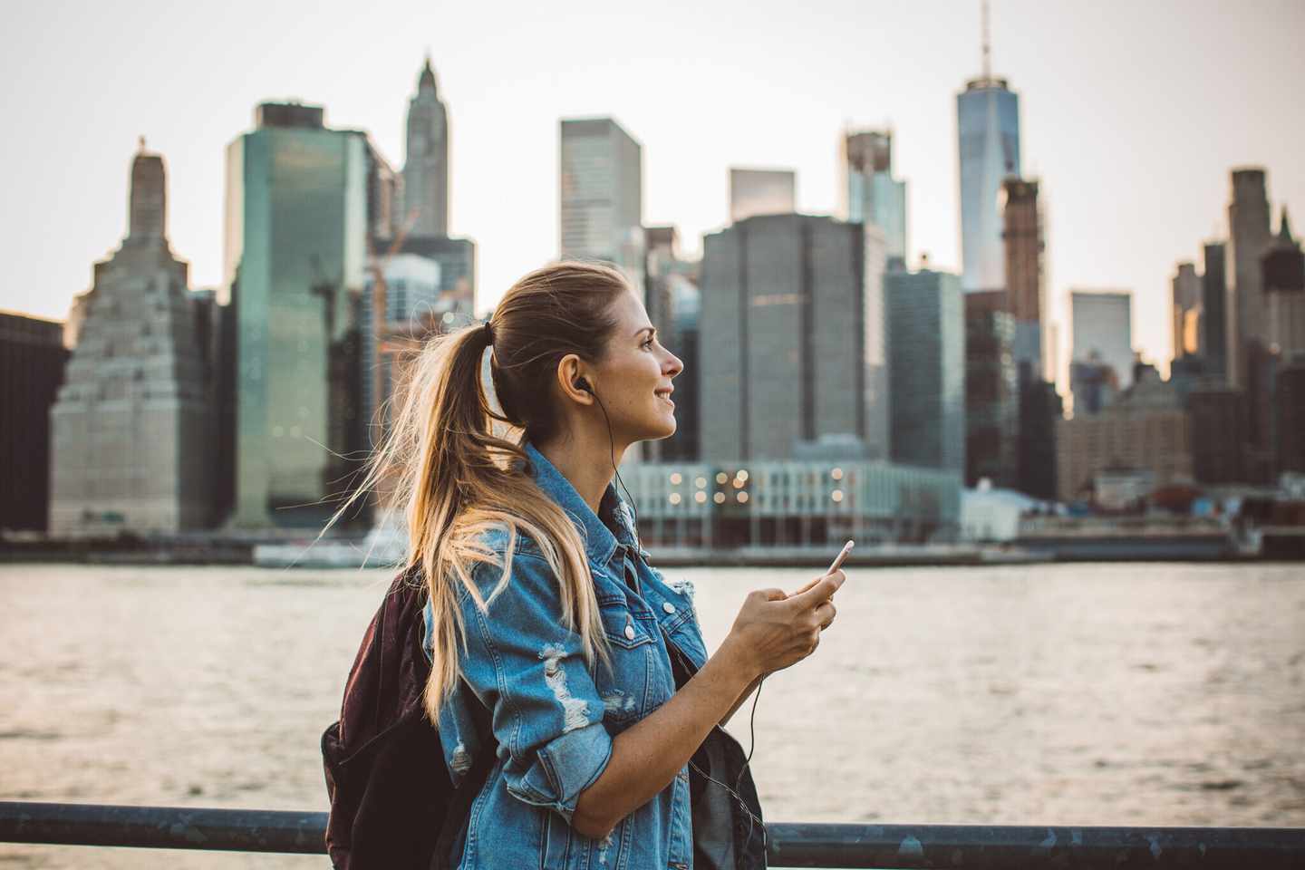 usa-new-york-frau-hoert-musik-am-wasser-im-hintergund-die-skyline-g-841123468.jpg