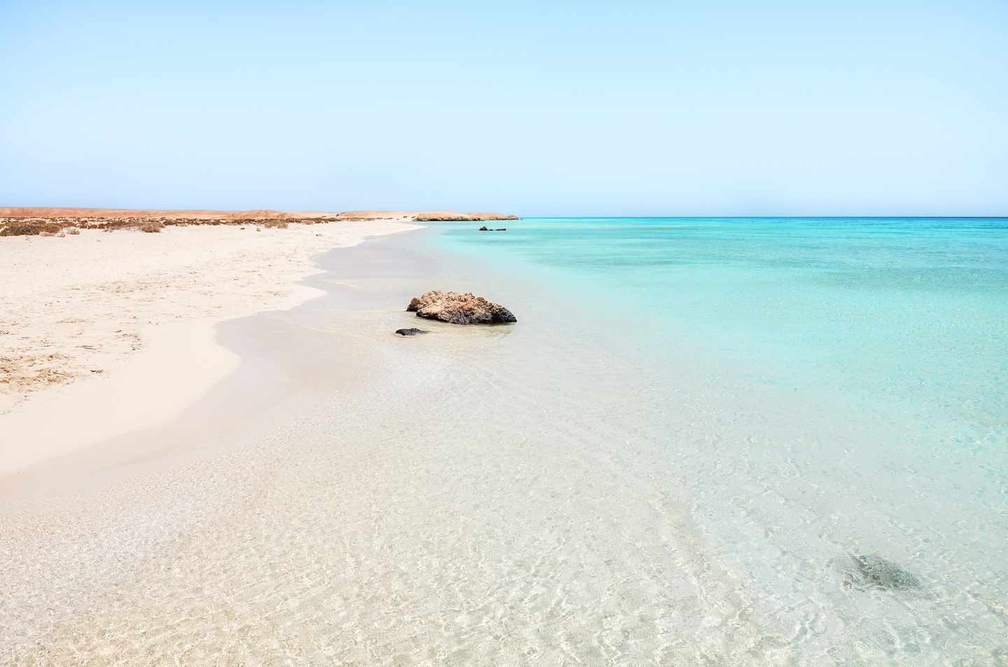 GettyImages-2154182270.jpg Feiner Sandstrand mit kristallklarem türkisfarbenem Wasser am Roten Meer in Ägypten