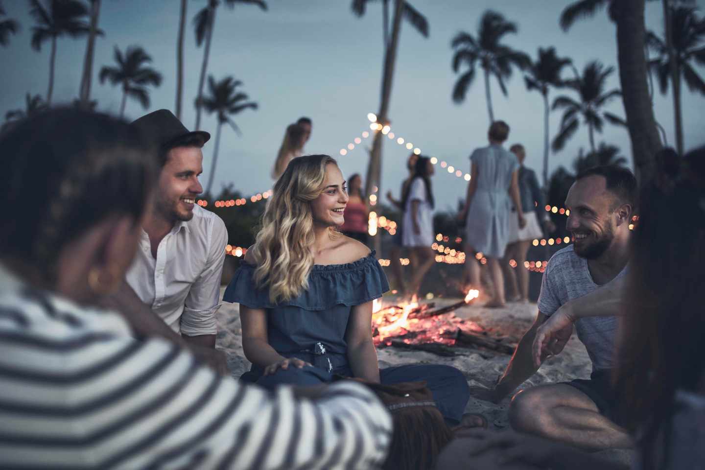 Gruppe von Freunden sitzt am Lagerfeuer am Strand