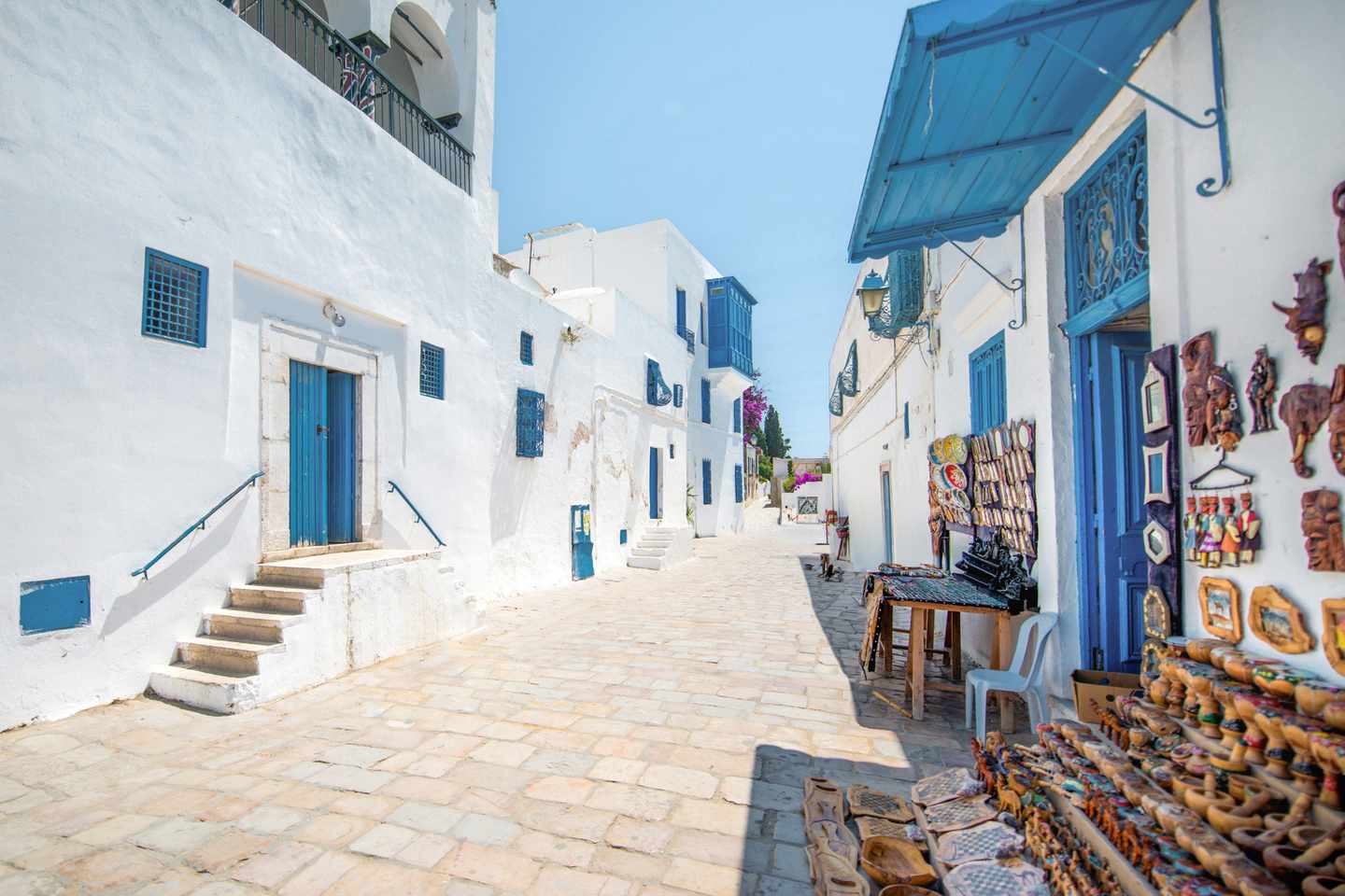 Weiße Häuser mit blauen Türen in der Medina von Hammamet, gepflasterte Gasse und traditionelle Architektur in Tunesien