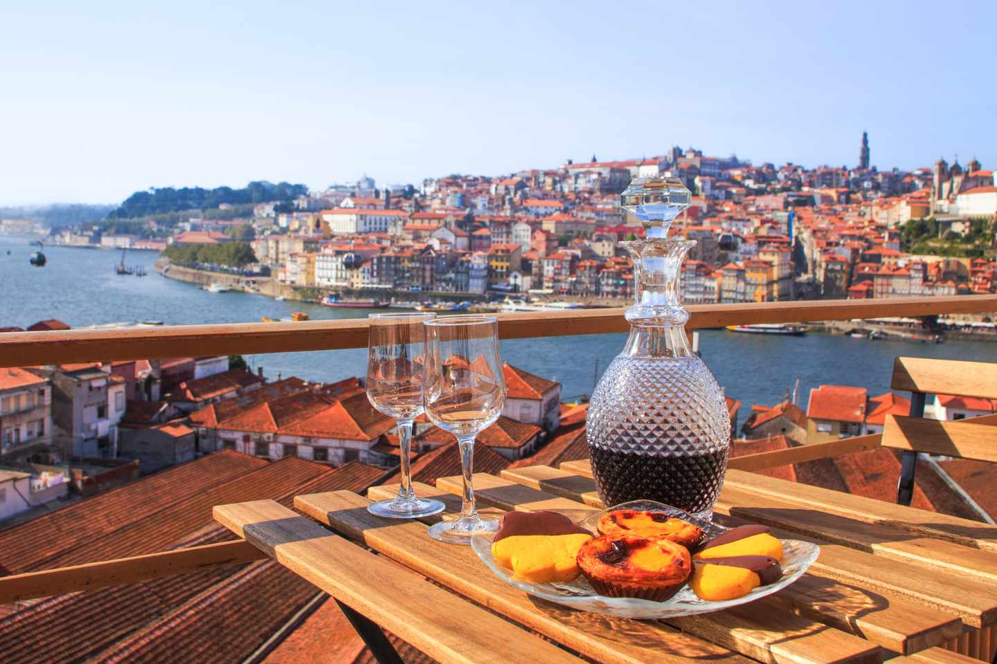 blt228a8852921e710e-portugal-porto-504635_AdobeStock_121946475_portwein-pasteis-de-nata.jpg Gedeckter Tisch mit einer Karaffe Portwein und Süßspeise Pastel de Nata