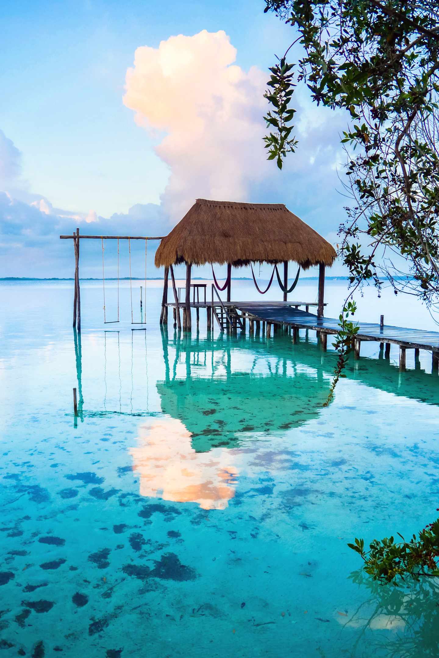 GettyImages-1257948455.jpg Mexiko-Urlaub: Leere Hängematten in einem Palapa über dem Wasser in der Karibik. Bacalar Lagune