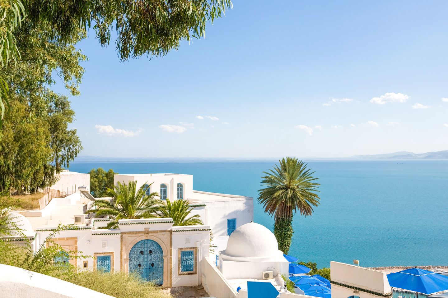 Weiße Gebäude mit blauen Türen und Kuppel über dem Meer im Künstlerort Sidi Bou Said in Tunesien
