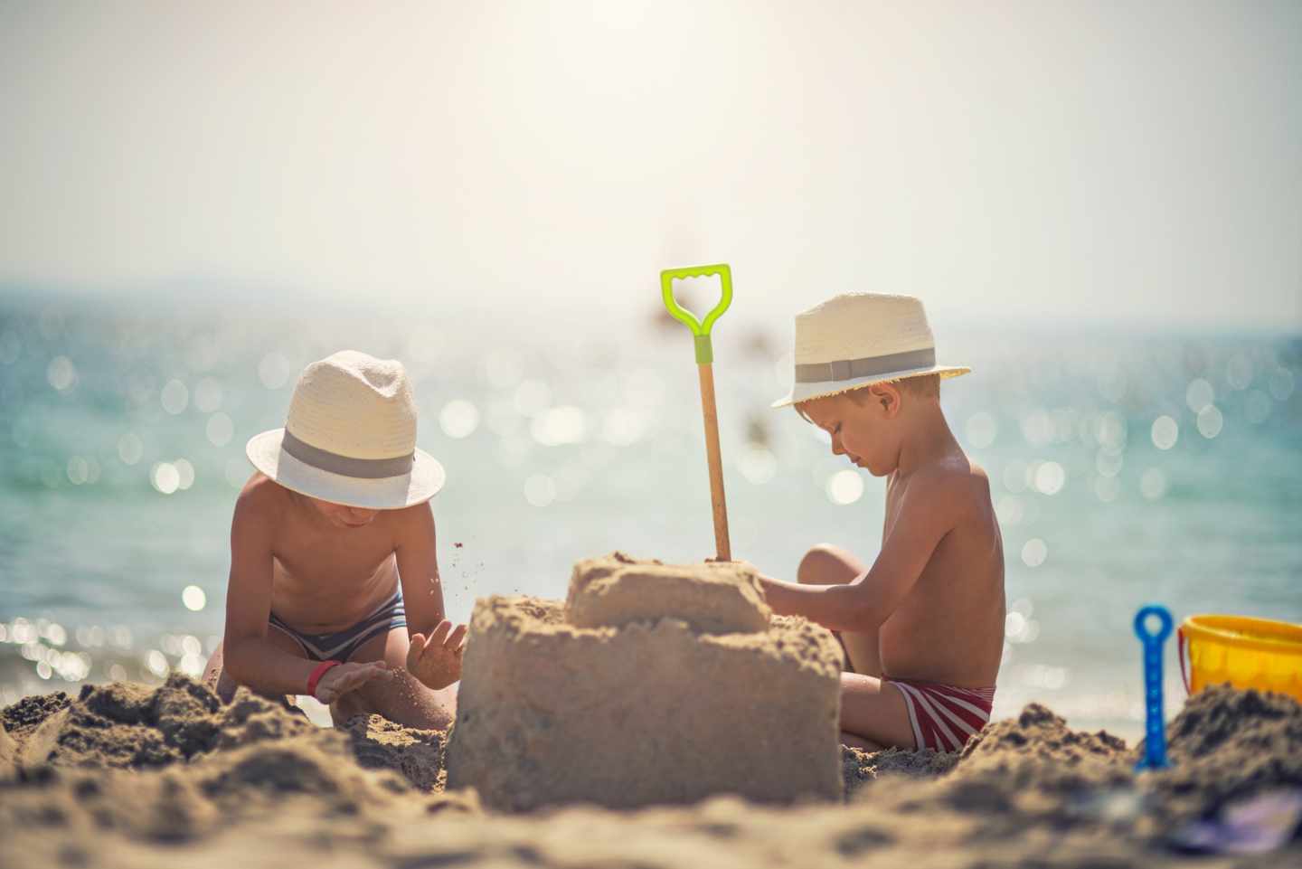 familienurlaub-zwei-jungen-bauen-eine-burg-am-strand-g-512628126.jpg