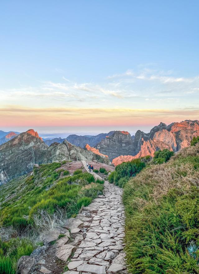 Wanderurlaub Madeira Steinweg mit Wandernden am Pico do Arieiro vor schroffen Berggipfeln im Morgenlicht auf Madeira, Portugal
