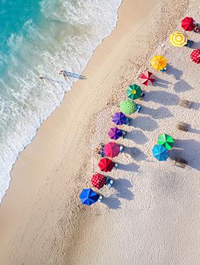 Jetzt entdecken Bunte Sonnenschirme an einem Strand