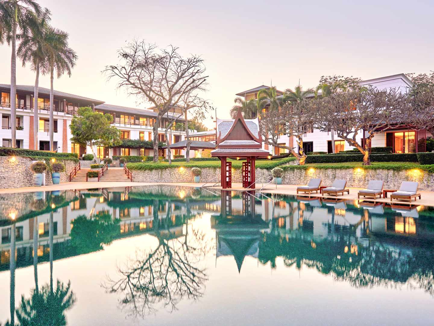 bltbb08c569338c4338-thailand-nong-kae-pool-h-chiva-som-health-resort-DER1541532.jpg Pool und dahinterliegende Zimmer auf drei Stöcken bei abendlicher Beleuchtung