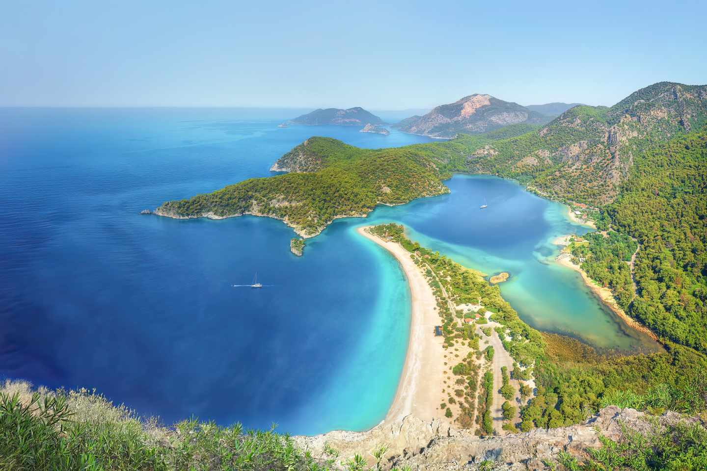 GettyImages-2273734336.jpg GettyImages-2273734336.jpg Aus der Vogelperspektive fotografierte Blaue Lagune mit grünen Bergen und türkisfarbenem Meer