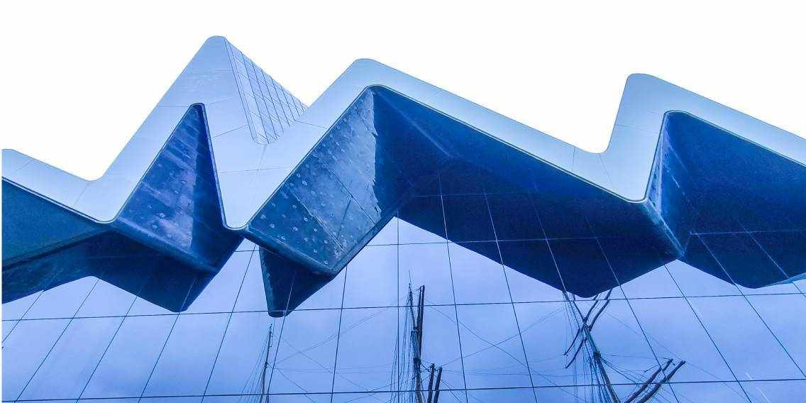 Moderne Glasfassade des Riverside Museum mit Spiegelung historischer Segelschiffe am River Clyde in Glasgow