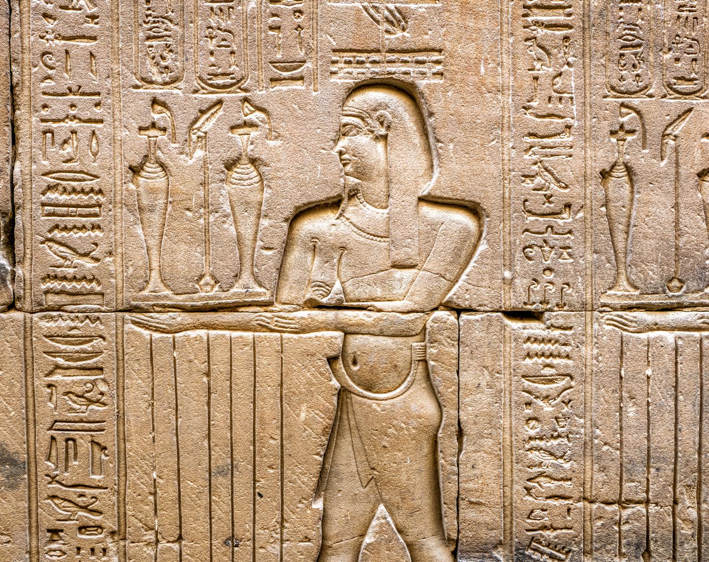 Steinrelief mit einer altägyptischen Figur und Hieroglyphen an einer Tempelwand des Edfu-Tempels in Ägypten