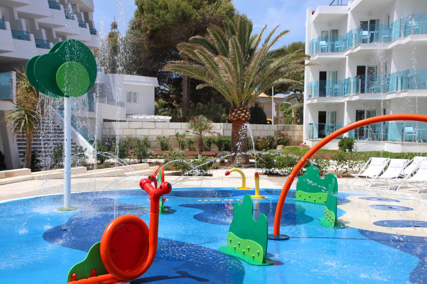 Beste Familienhotels Mallorca – Kinder-Wasserspielplatz im Iberostar Selection Playa de Muro Village mit bunten Spielen und sprudelnden Wasserfontänen