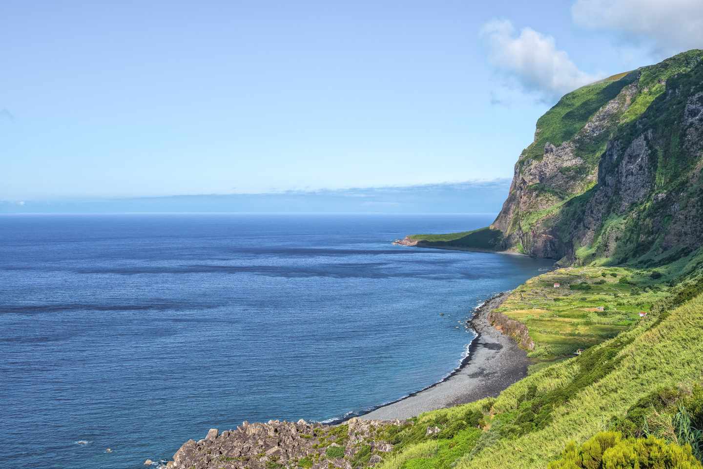 Fajã de Lopo Vaz auf Flores mit grüner Steilküste, Kiesstrand und weitem Blick über den Atlantik