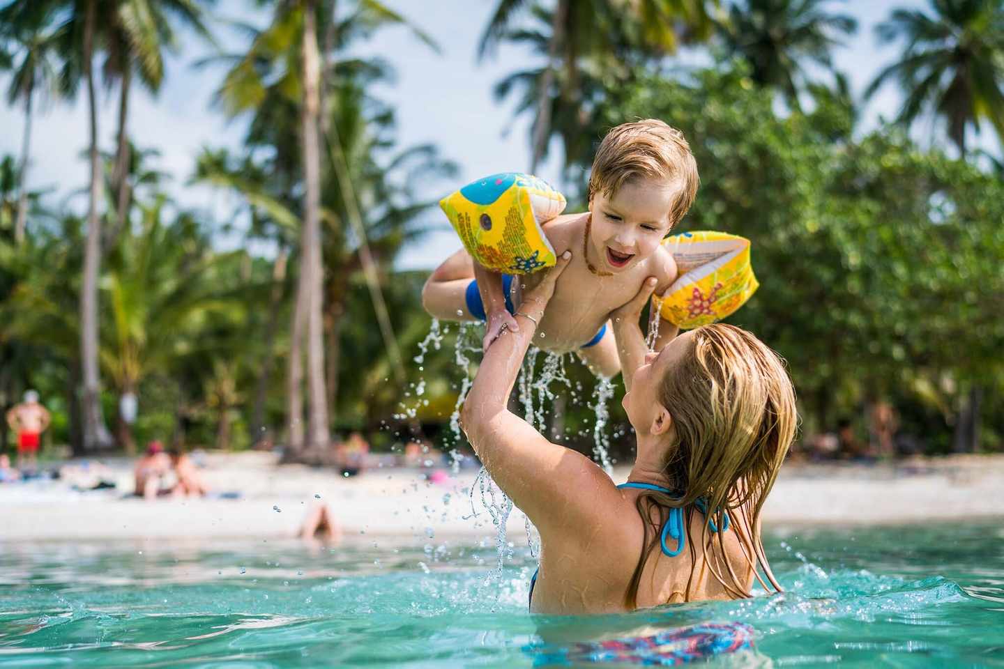 thailand-familienurlaub-glueckliche-kleine-junge-spass-im-meer-waehrend-er-von-seiner-mutter-statt-g-941259962.jpg