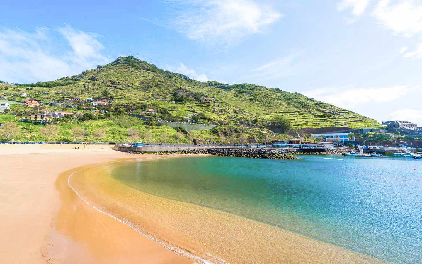 Sandstrand von Machico auf Madeira mit geschützter Bucht, türkisblauem Wasser und grünen Berghängen im Hintergrund