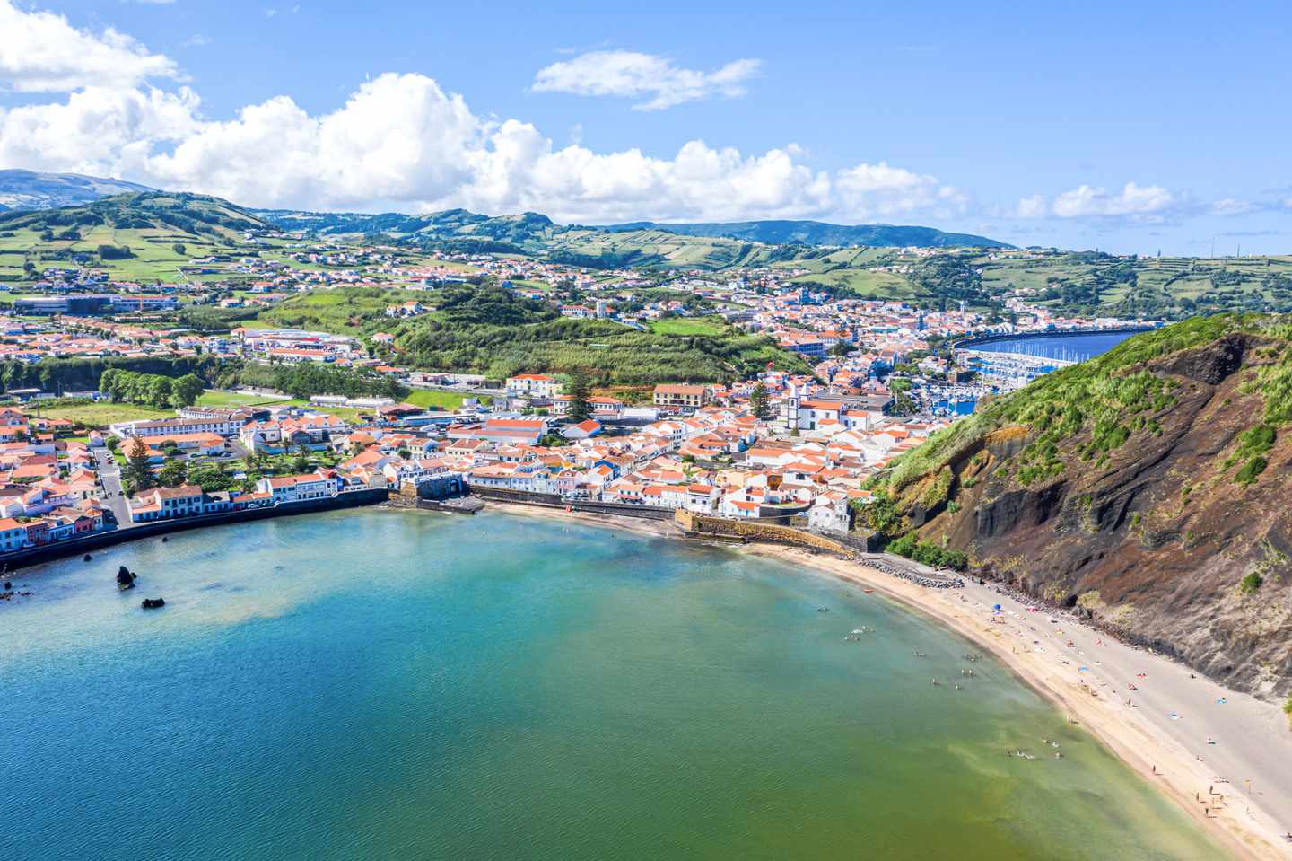 Baía do Porto Pim auf Faial mit Sandstrand, Horta und grünem Vulkanhang im Hintergrund