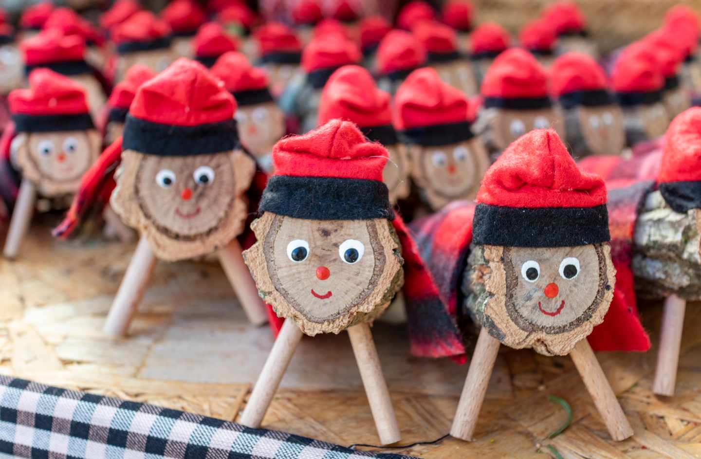 Katalanische Caga-Tió-Holzfiguren mit Gesichtern und roten Mützen auf einem Weihnachtsmarkt