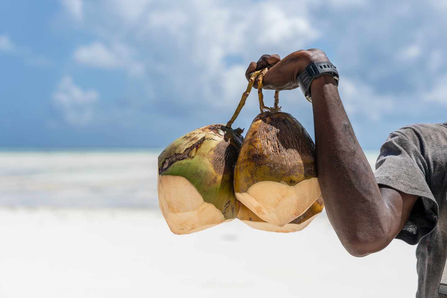 Sansibar Essen: Mann verkauft Kokosnüsse am Sandstrand