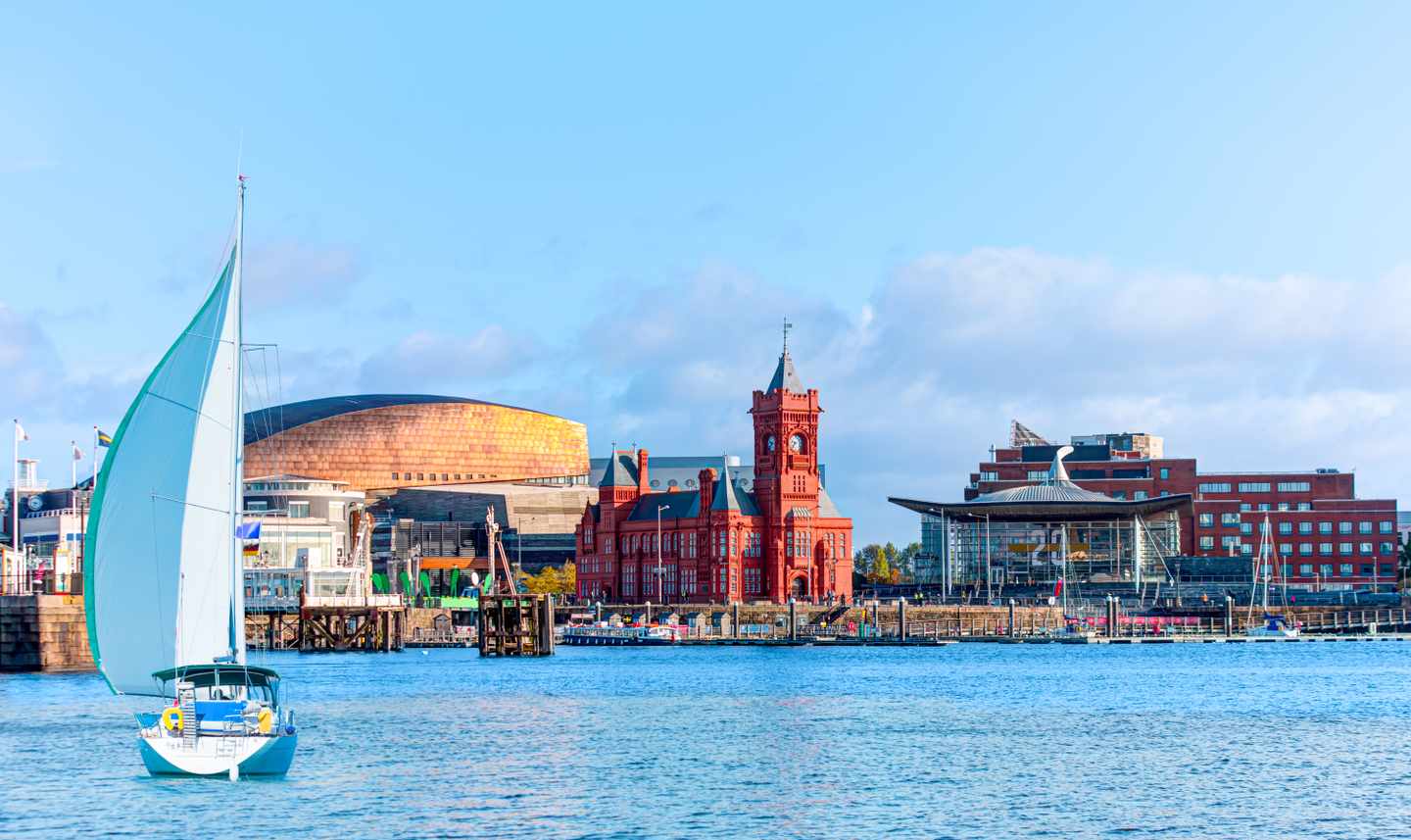 Segelboot auf der Cardiff Bay vor dem Wales Millennium Centre und historischen Hafengebäuden in Cardiff