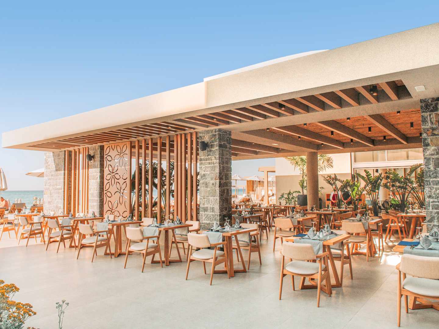 blt3c7cf3fe9da44512-griechenland-kreta-sentido-unique-blue-gastronomie-aussenbereich-DER1405948.jpg Außenbereich im Sentido Unique Blue Resort auf Kreta mit überdachter Terrasse, Holztischen, Polsterstühlen und Blick zum Meer