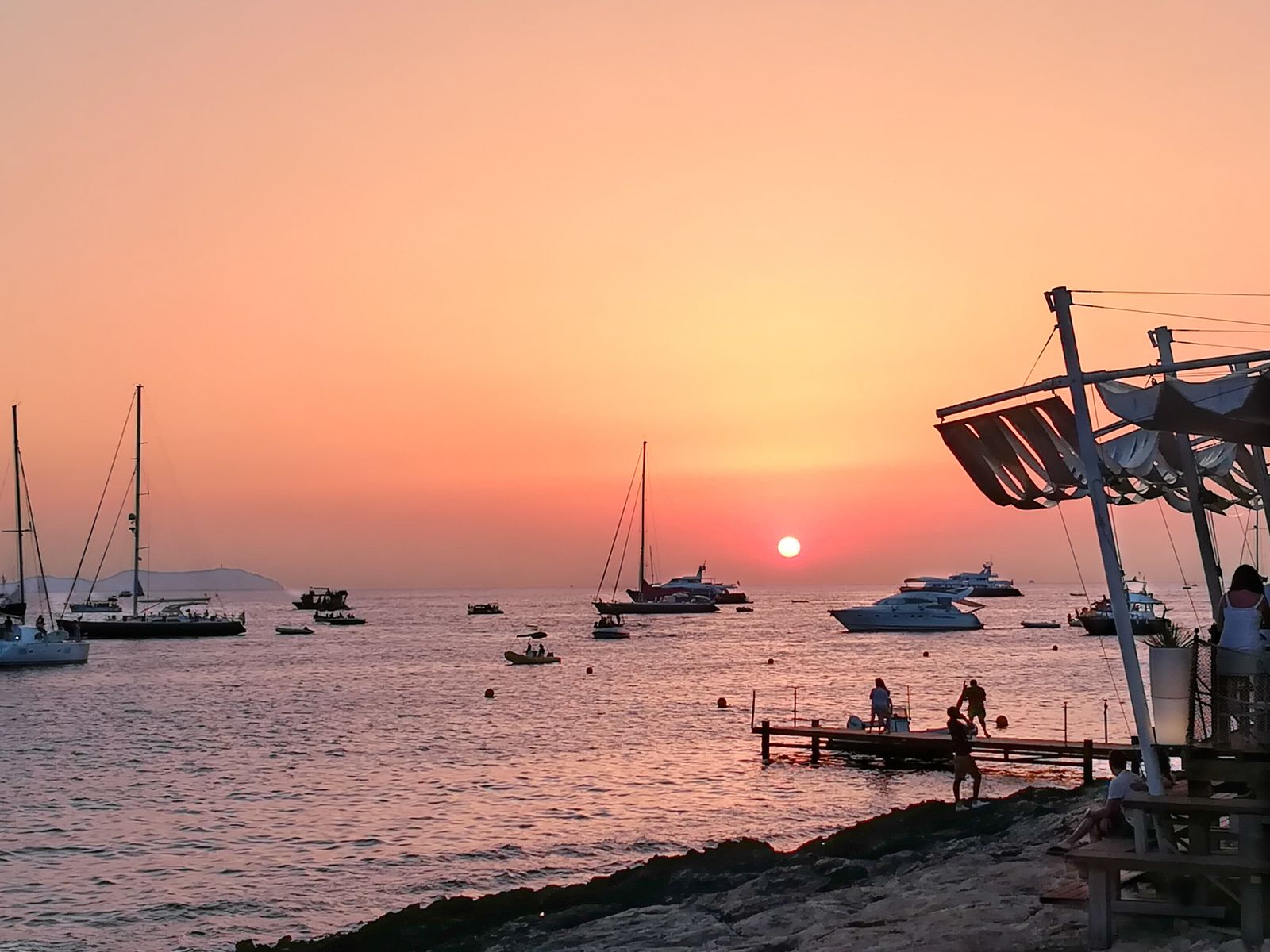 Sonnenuntergang am berühmten Café Del Mar einer der beliebtesten Ibiza Sunset Bar mit Blick auf Segelboote und das Meer