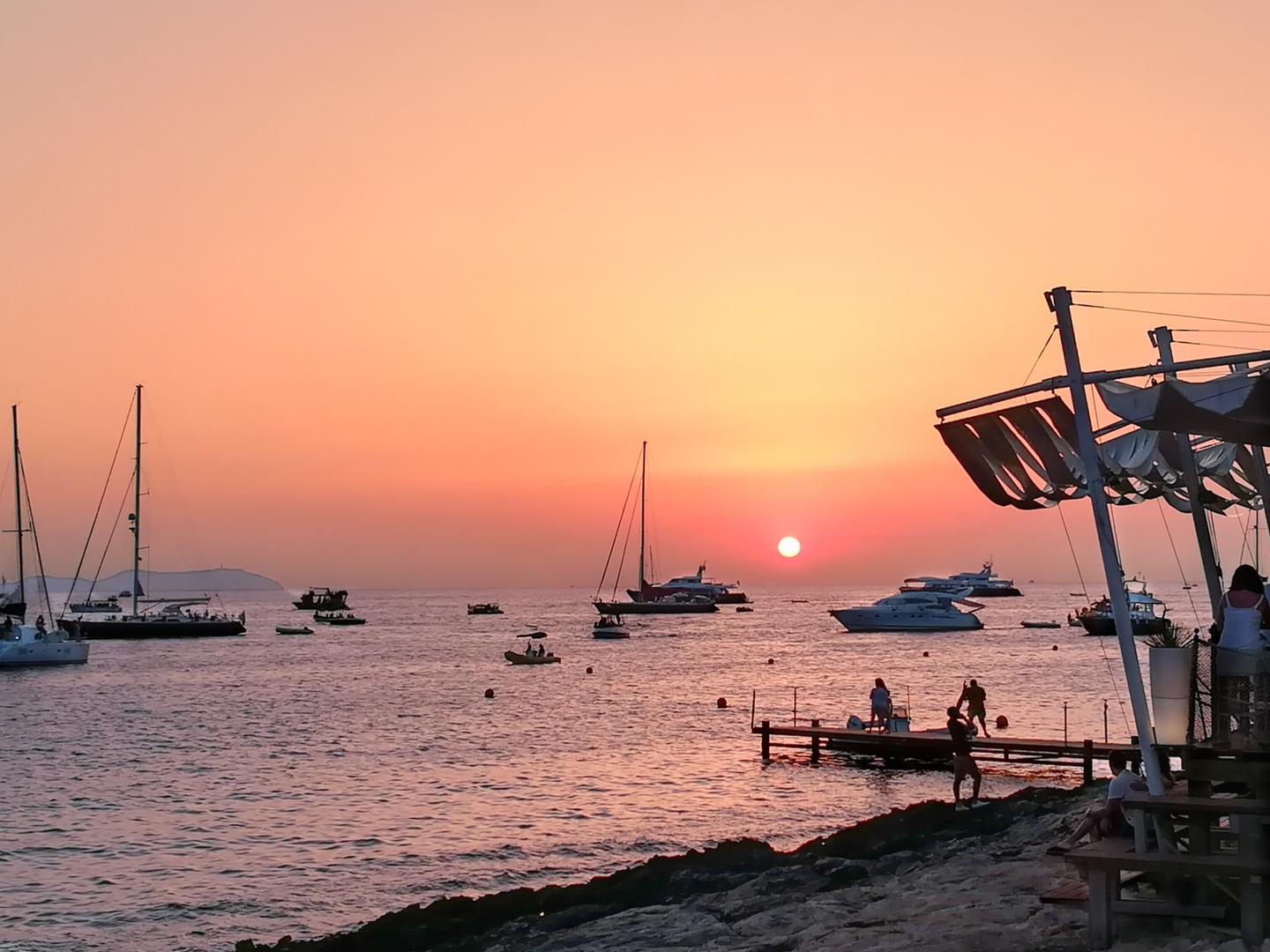 Sonnenuntergang am berühmten Café Del Mar einer der beliebtesten Ibiza Sunset Bar mit Blick auf Segelboote und das Meer