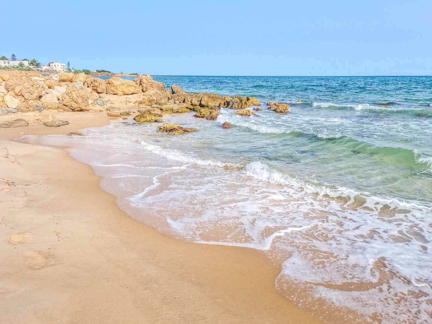 Sandstrand bei Hammamet mit hellen Felsen, sanften Wellen und türkisblauem Mittelmeer an der tunesischen Küste