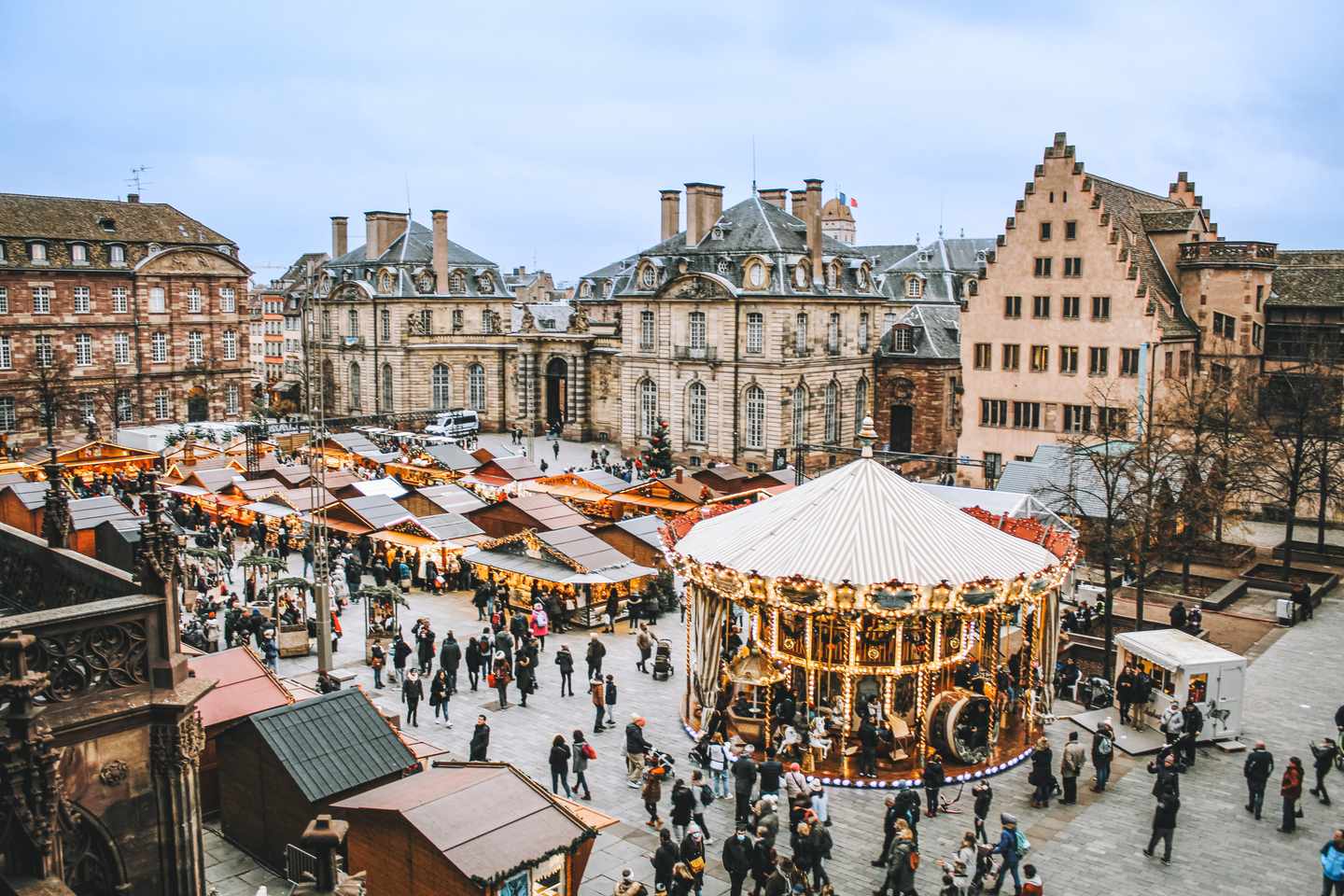 Weihnachtsmarkt in Straßburg mit beleuchteten Marktständen und Karussell vor historischen Gebäuden